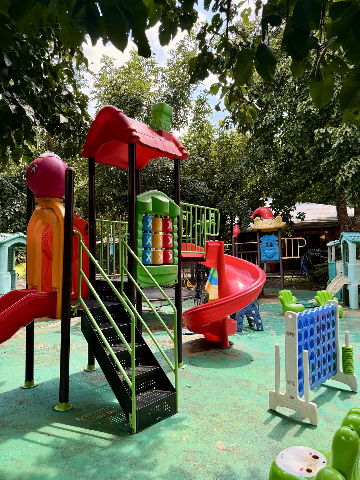 Colorful slides and play equipment in a shaded outdoor playground