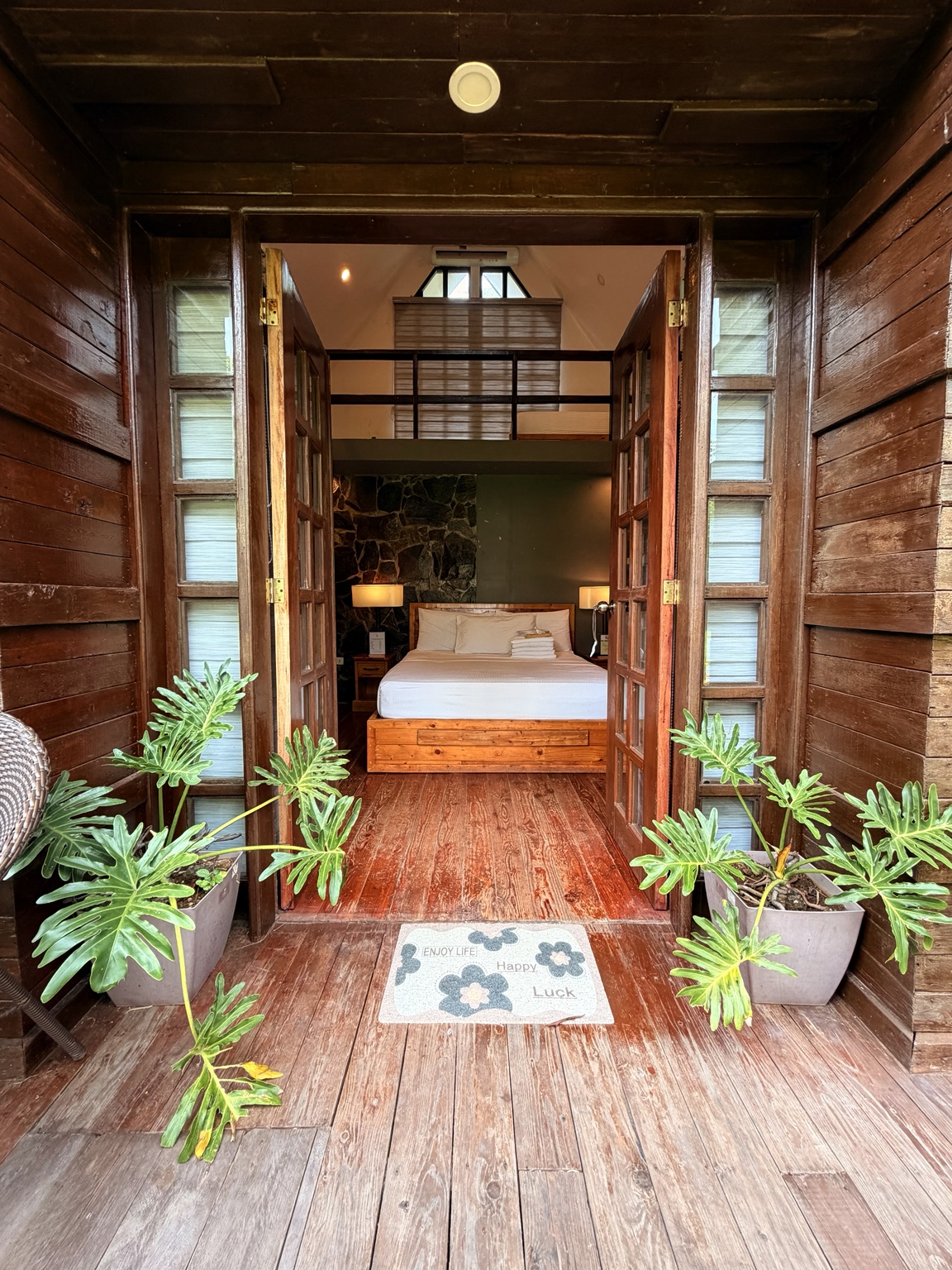 Open villa doors leading to a wooden interior and bed